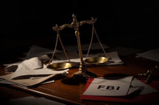 Tilted scales of justice on dark desk surrounded by scattered legal documents and government folders in dramatic lighting