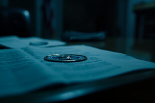 Government memo with official seal on wooden desk surrounded by scattered papers in dimly lit office