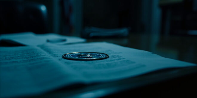 Government memo with official seal on wooden desk surrounded by scattered papers in dimly lit office