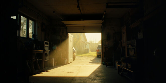 Morning sunlight illuminates the interior of a residential garage with open door showing safe hiding space