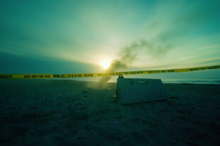 Evidence markers and police tape cordoning off a crime scene on a deserted Baltic Sea beach at dawn
