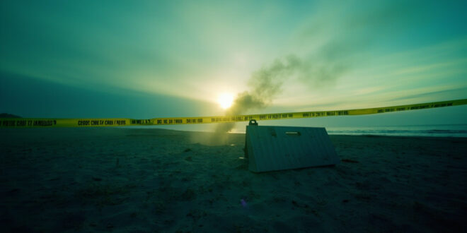 Evidence markers and police tape cordoning off a crime scene on a deserted Baltic Sea beach at dawn