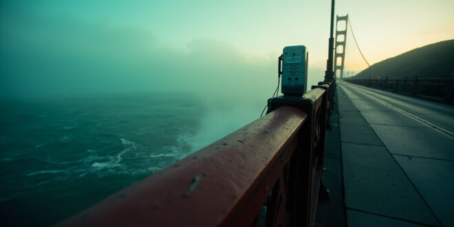Golden Gate Bridge safety railing with emergency call box overlooking San Francisco Bay waters below.
