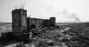 Damaged concrete barrier posts and abandoned military equipment scattered across empty contested borderland.