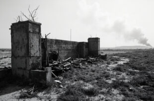Damaged concrete barrier posts and abandoned military equipment scattered across empty contested borderland.