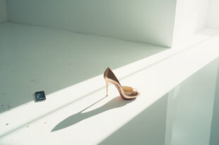 Elegant rose gold stiletto heel next to abandoned smartphone displaying viral challenge in minimalist studio with dramatic lighting
