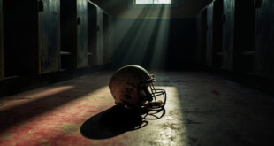 Football helmet lying sideways on concrete locker room floor with dramatic lighting creating long shadows
