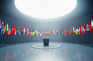 Twenty-six national flags arranged in semicircle around empty diplomatic conference podium in blue and gold minimalist setting