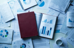 Bound research report surrounded by educational policy documents and statistical charts on institutional desk