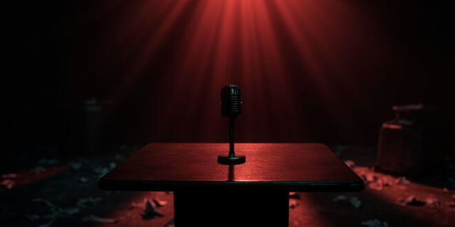 Empty news desk with microphone and scattered documents in darkened television studio