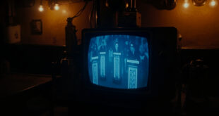 Television screen in cozy pub showing quiz show set with empty contestant podiums and game show lighting.