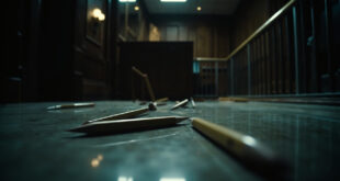 Wooden pencils scattered across polished courtroom floor near judicial bench with security barriers visible