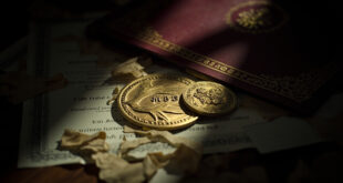MBE medal sits beside torn certificate fragments on wooden desk surface with formal documents