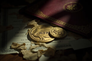 MBE medal sits beside torn certificate fragments on wooden desk surface with formal documents