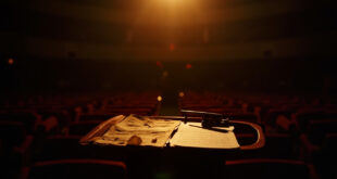Empty concert hall with conductor's podium illuminated by single spotlight, scattered sheet music visible
