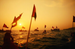Multiple boats with Palestinian flags sailing from Barcelona port at sunset carrying medical and food supplies.
