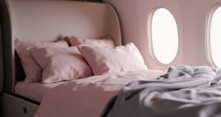 Private jet cabin interior with comfortable bed covered in soft blankets and pillows