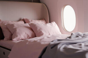 Private jet cabin interior with comfortable bed covered in soft blankets and pillows