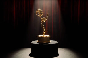 Golden Emmy trophy on dark podium under dramatic stage spotlights