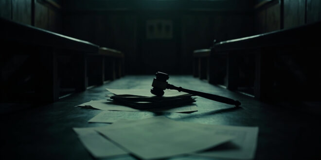 Dark courthouse interior showing wooden judge bench, gavel, and scattered legal documents on polished surface.