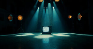 Dark television studio with bright stage lights casting dramatic shadows across an empty performance area