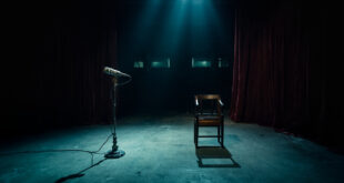 Television studio stage with microphone stand under spotlight, empty chairs and curtained backdrop in dramatic lighting