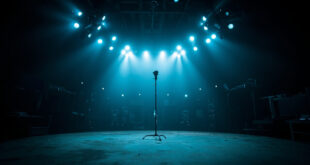 Empty television studio with single microphone stand illuminated against dark backdrop of silent broadcast equipment