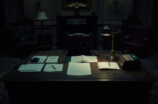 Empty government office with formal desk, scattered official documents, and vacant leather chair in dim lighting.