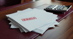 Budget documents and financial papers spread across conference table with calculator and official stamps