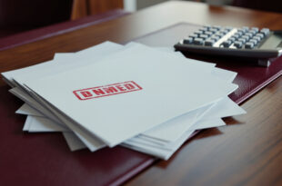 Budget documents and financial papers spread across conference table with calculator and official stamps