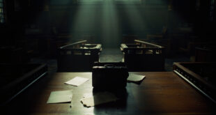 Open leather briefcase on wooden table in ornate government building with scattered official documents