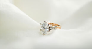 Close-up of sparkling diamond engagement ring on white silk fabric with soft lighting