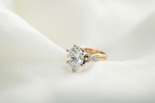 Close-up of sparkling diamond engagement ring on white silk fabric with soft lighting