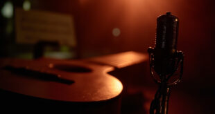 Recording studio setup with acoustic guitar, microphone, and warm lighting creating intimate musical atmosphere