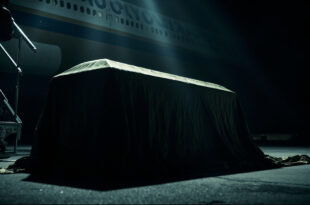 Draped mahogany coffin positioned on aircraft steps with official government plane in background on airport tarmac