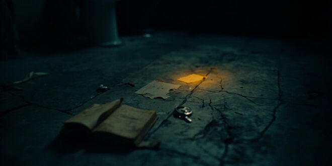 Dark bathroom floor with open book, dim lighting creating shadows across cold tiles