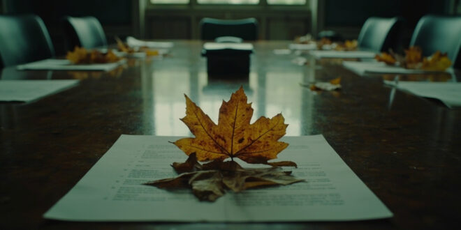 Withered autumn leaves scattered on empty government conference table in dimly lit chamber