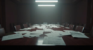 Empty conference table with budget papers and folders scattered across polished wood surface in government meeting room