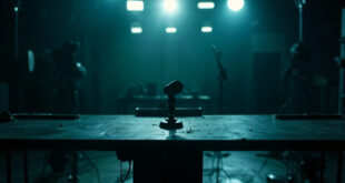 Empty television studio with single microphone on dark desk under dim studio lighting