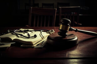 Stethoscope and gavel on wooden desk with legal documents in dimly lit chamber