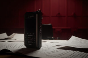 Audio recorder on desk with redacted documents, empty chairs, and official government office setting