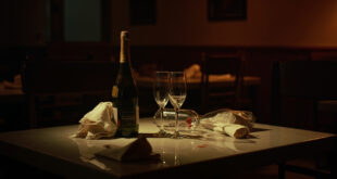Empty wine glasses and champagne bottles on restaurant table with dim lighting and scattered napkins