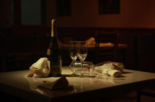 Empty wine glasses and champagne bottles on restaurant table with dim lighting and scattered napkins