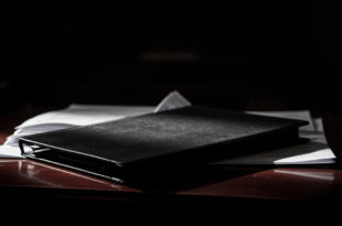 Closed psychiatric evaluation folder with official seals on wooden courtroom bench in secure institutional setting