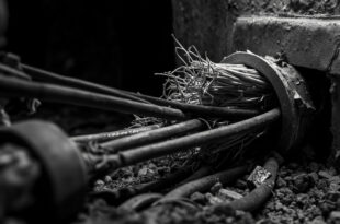 Severed railway signal cables protruding from concrete underground junction box with cut wire ends visible