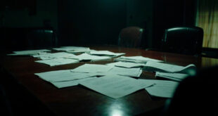 Empty boardroom table with scattered official documents and vacant leather chairs in dramatic lighting