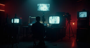 Dark control room with multiple TV screens displaying static and test patterns, empty director chair in foreground