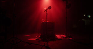 Empty television studio with host desk, microphone, and production lights in darkness representing broadcast suspension