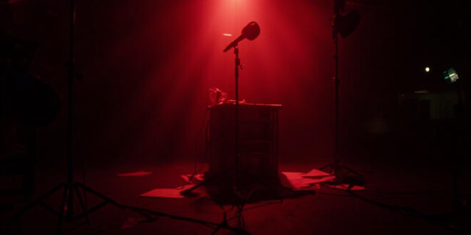 Empty television studio with host desk, microphone, and production lights in darkness representing broadcast suspension