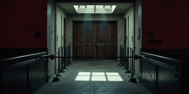 Empty Capitol corridor with metal security barriers and closed wooden doors under dim institutional lighting